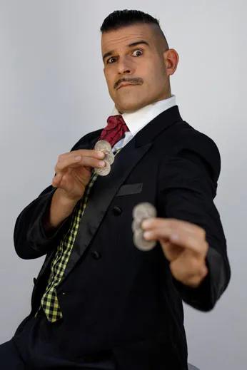 Butler Herrmann macht sich seinen rosa Schlips zurecht, trägt einen schwarzen Frack und eine gelbe Weste, sein Blick ist streng und seine Haare sind nach hinten gegelt