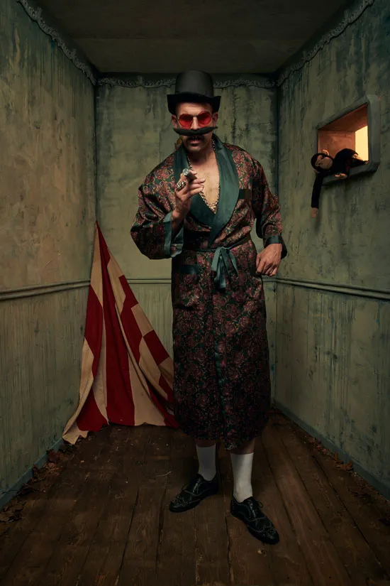 Zirkus Direktor Michal Popowize sitzt in roter Uniform mit riesigem Oberlippenbart, blickt in die Kamera, trägt eine schwere Goldkette um den Hals und prunkvolle Goldringe, schwarzer Hintergrund