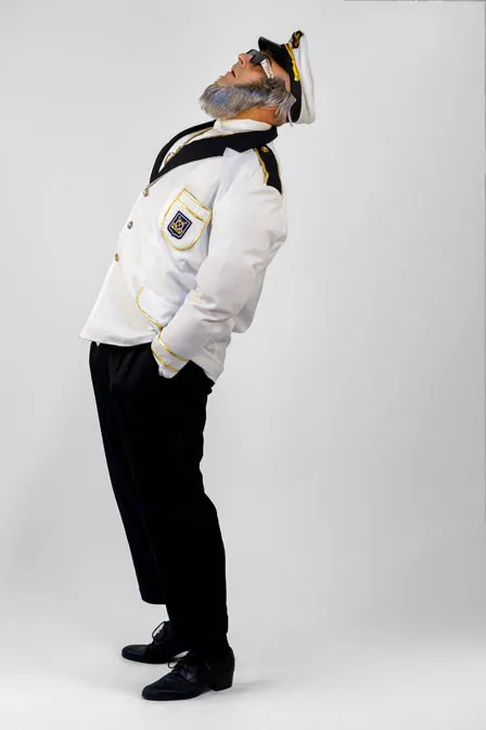 Alter Kapitän Sören Bleibart trägt eine weiße Kapitäns-Uniform und schwarze Sonnenbrille, eine Goldkette mit großem goldenen Anker um den Hals